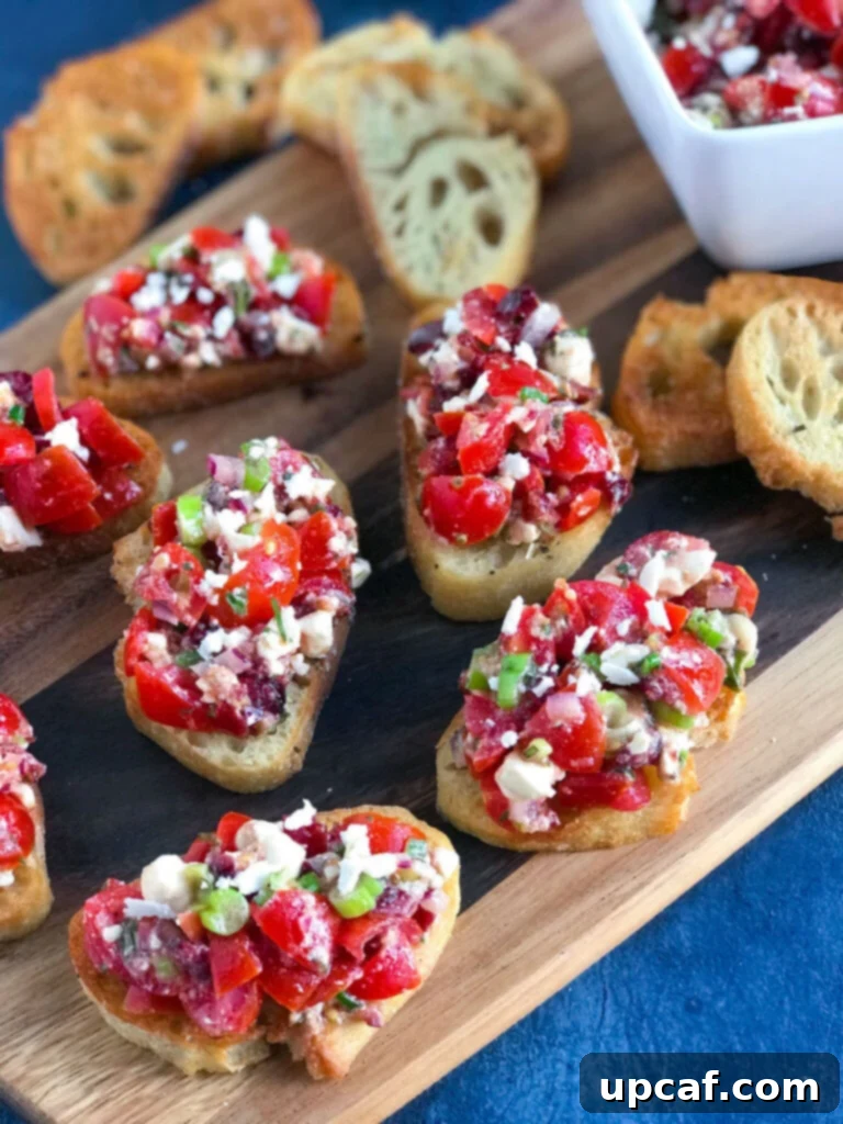 A serving platter filled with Feta Bruschetta on crostini, garnished with fresh basil leaves.