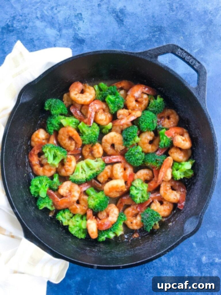 Sizzling Teriyaki Shrimps cooking in a cast iron skillet with broccoli, glistening in the sauce.