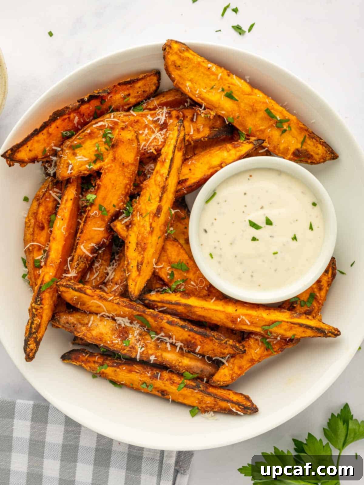 A bowl of sweet potato wedges with dipping sauce.