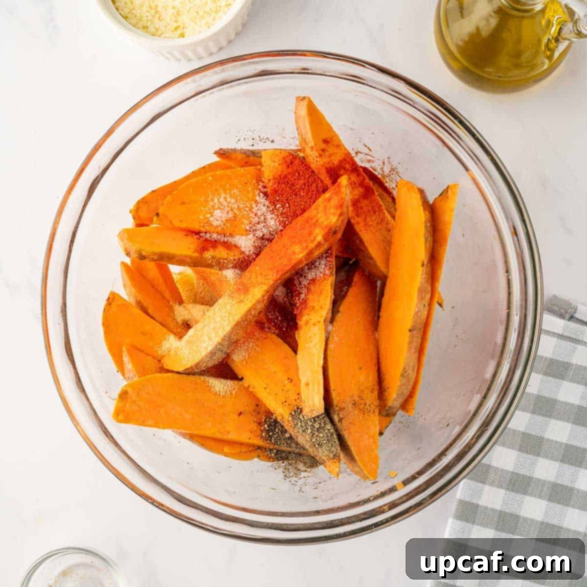 Seasoning is poured over sliced sweet potatoes.