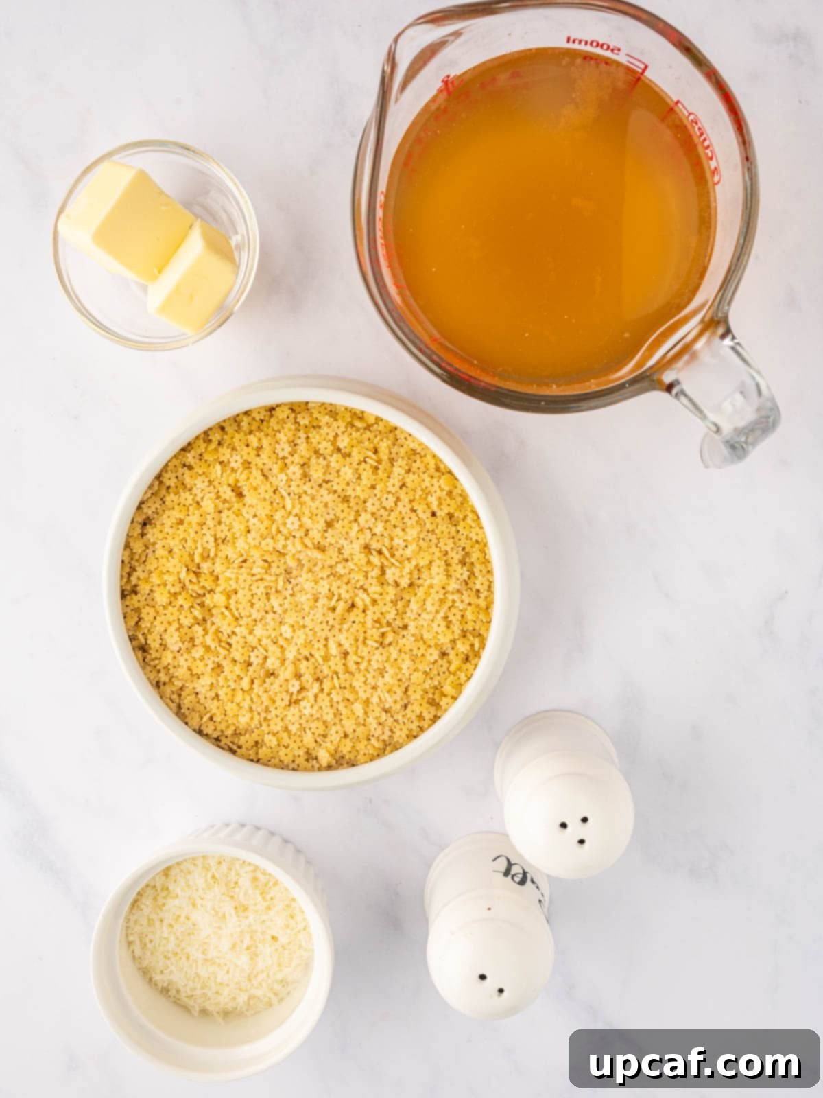Ingredients needed for pastina pasta, including chicken broth, stelline pasta, butter, and Parmesan cheese.