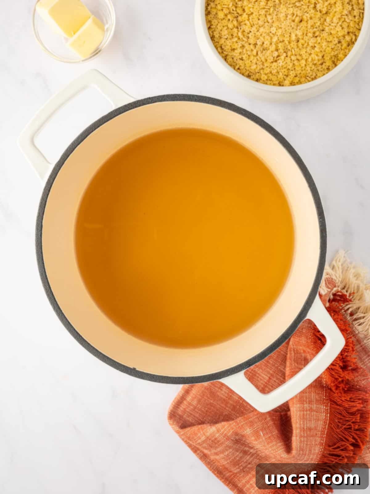 Chicken broth is heated to a boil in a dutch oven.