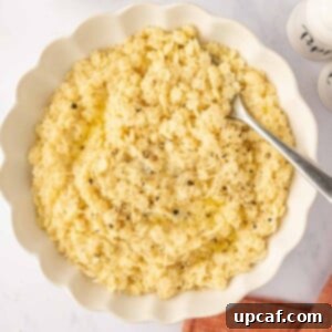 A spoon rests in a white bowl of pastina pasta.
