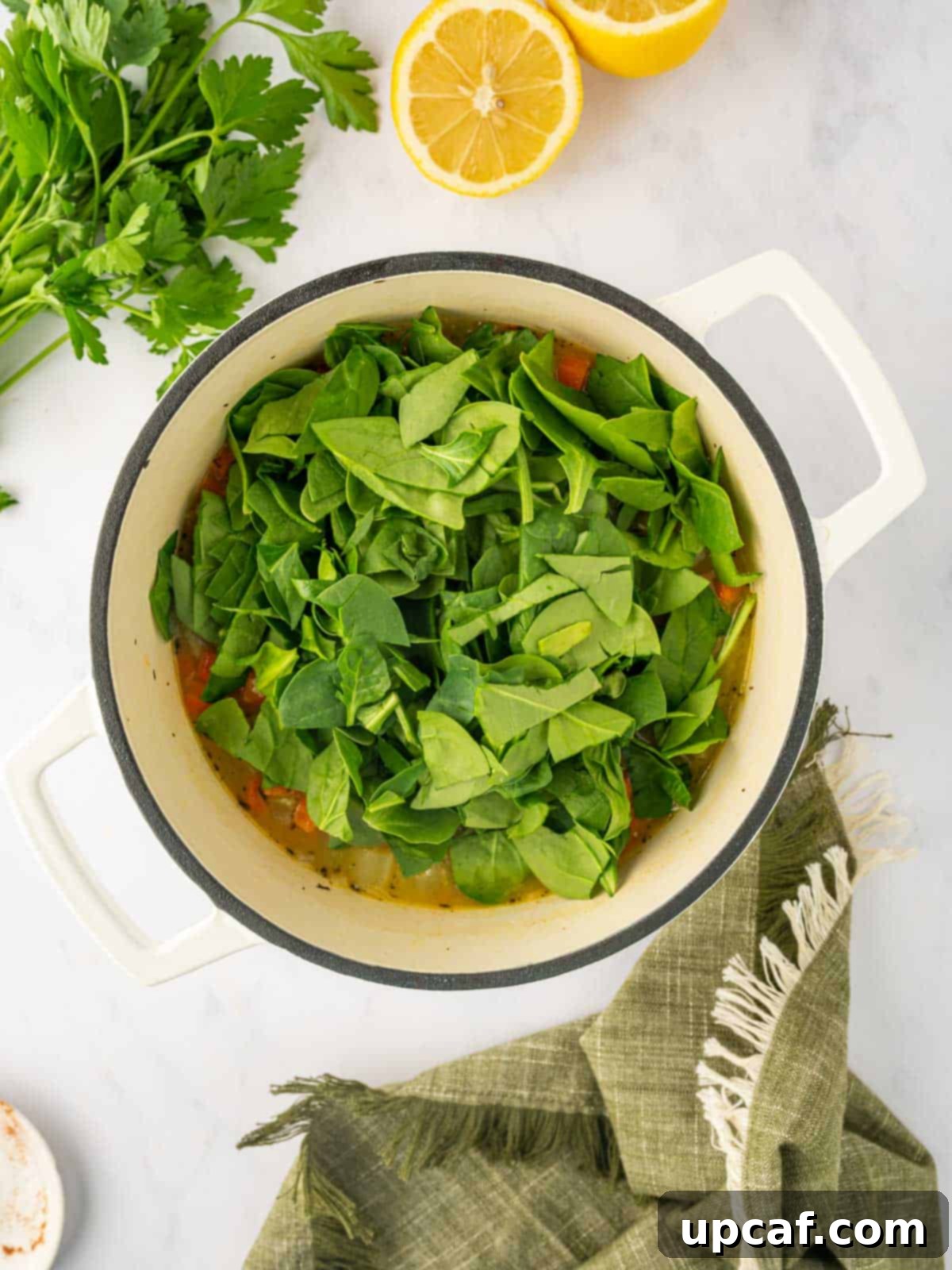 Comforting Italian Pastina Soup 7 Chopped fresh spinach being added to the simmering Pastina soup.