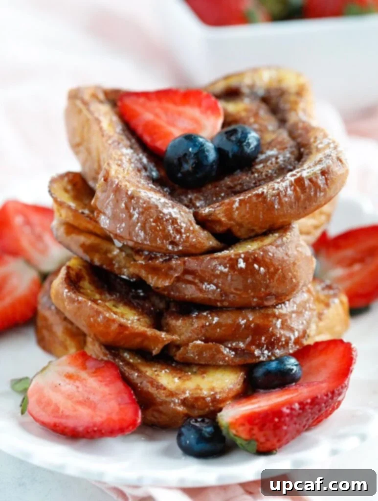 Cinnamon Swirl French Toast A tall stack of freshly made Cinnamon Swirl French Toast, topped with fresh berries and a light dusting of powdered sugar.