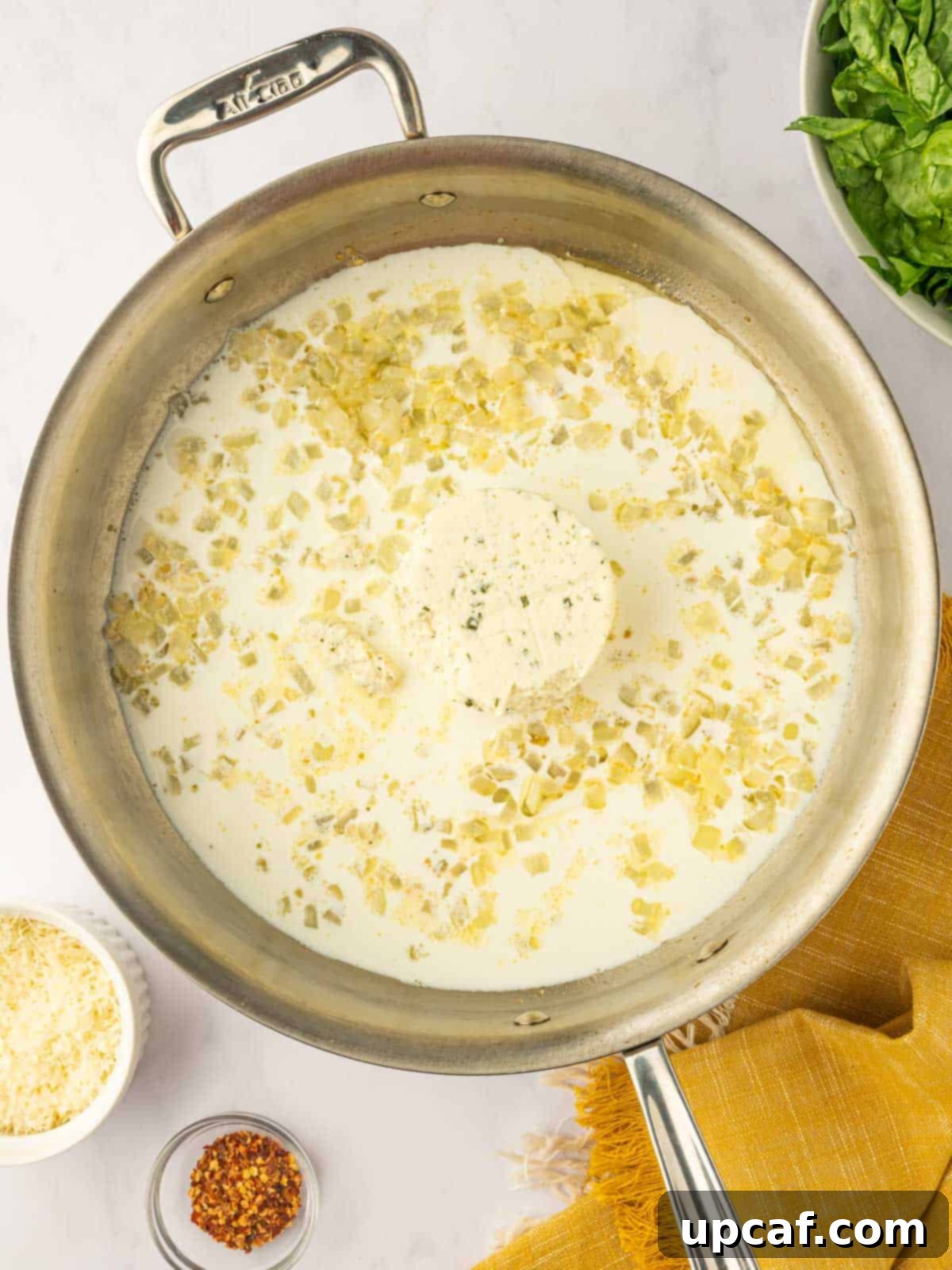 Boursin cheese melting gently into heavy cream in a skillet, creating a smooth, rich sauce base.