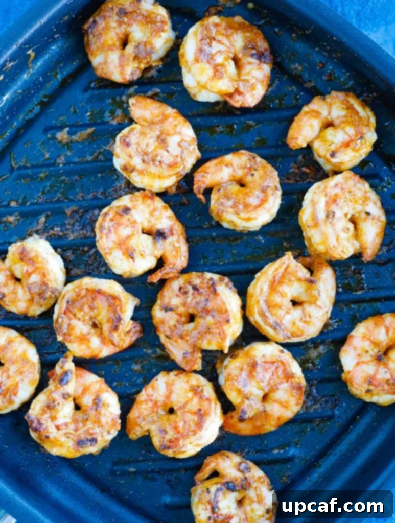 Prepping Perfect Shrimp Tacos 2 Close-up shot of seasoned shrimp cooking in a grill pan, showing their vibrant pink color and enticing sear marks.