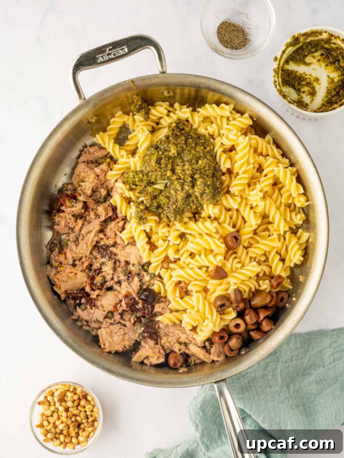Mediterranean Tuna Pesto Pasta 6 Cooked fusilli pasta, Kalamata olives, and basil pesto being tossed together in a large skillet with the sautéed tuna mixture.