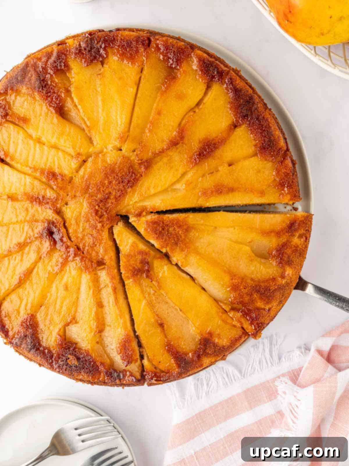 Caramelized Pear Crown Cake 16 A slice of pear upside down cake is cut from a whole cake, ready to serve.