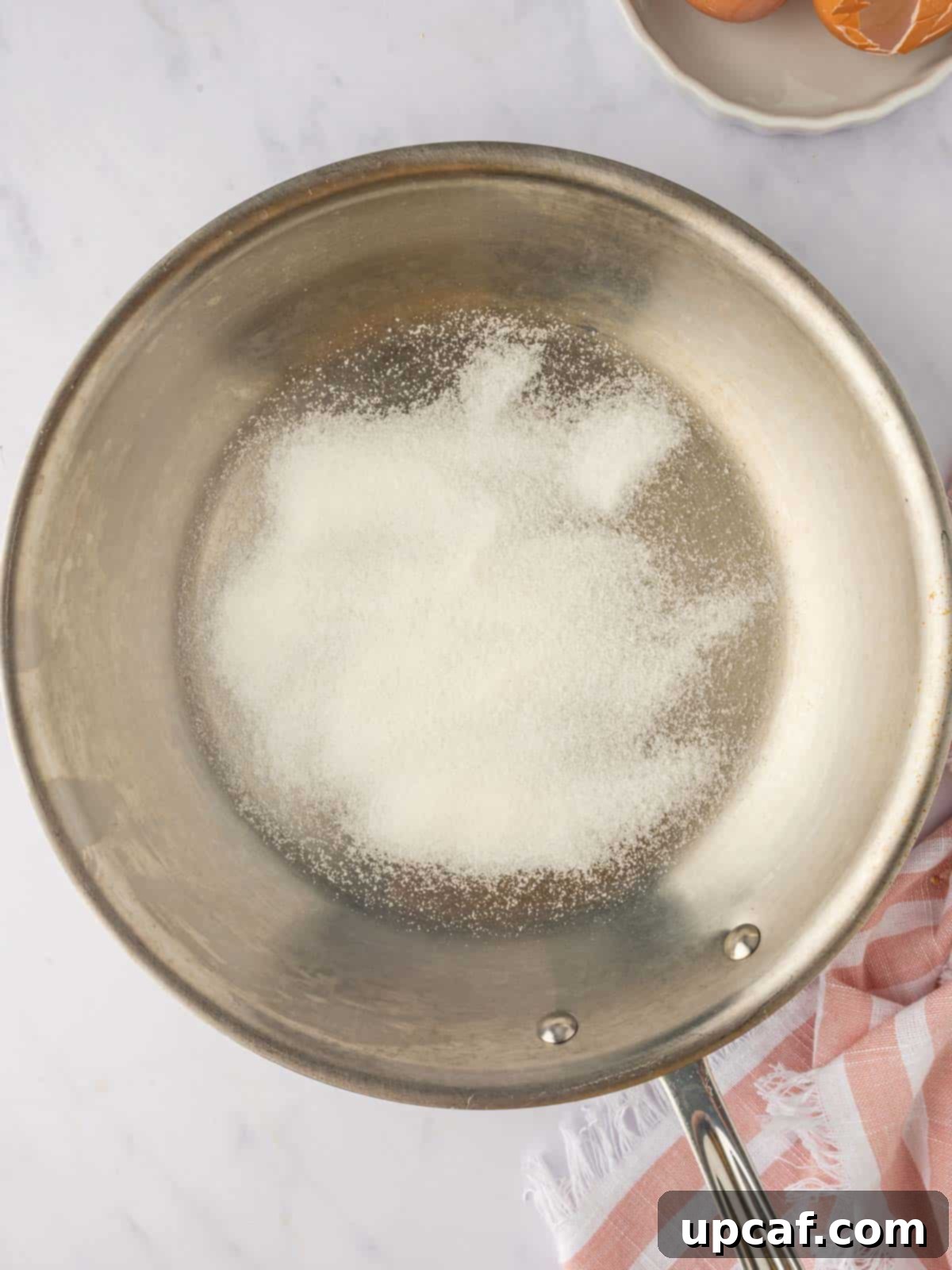 Caramelized Pear Crown Cake 4 Sugar is browned in a skillet for caramel sauce, showing golden granules.