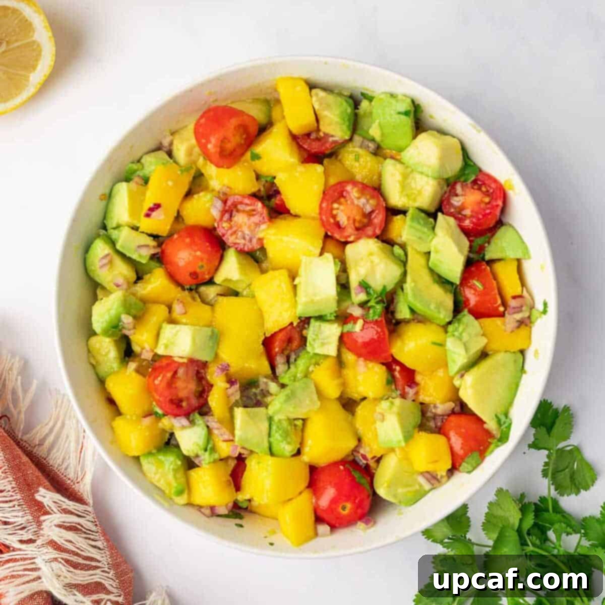 The process of preparing the dressing and tossing it with the avocado mango salad ingredients.