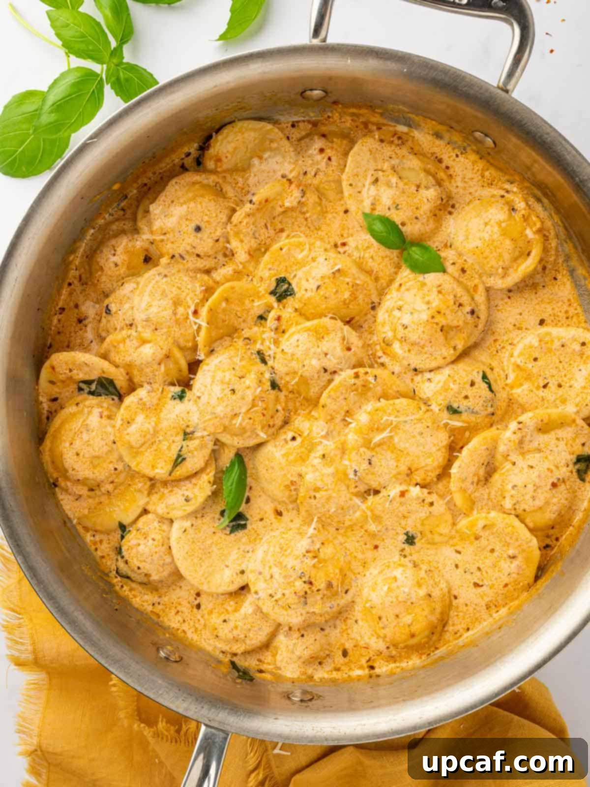 A large skillet filled with creamy Four Cheese Ravioli Pasta, perfectly tossed in a rich sun-dried tomato pesto sauce, ready to serve.