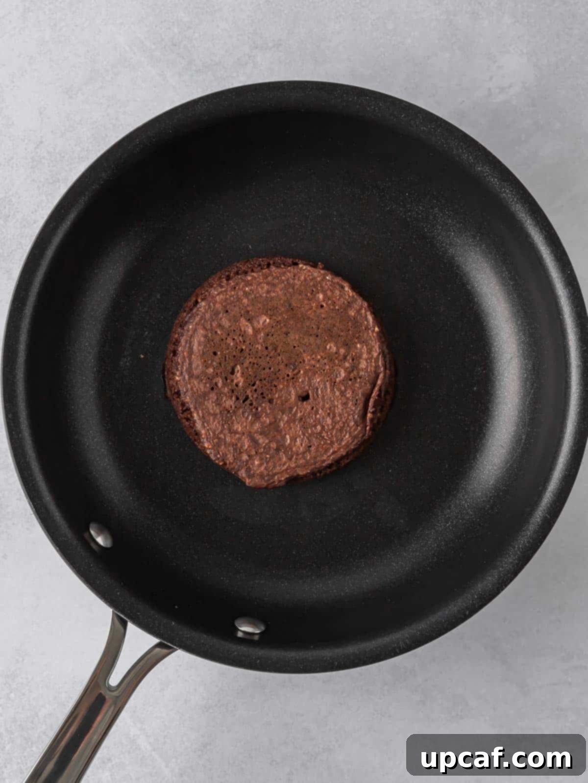 Ultimate Chocolate Protein Stacks 7 A chocolate pancake cooks in a skillet.