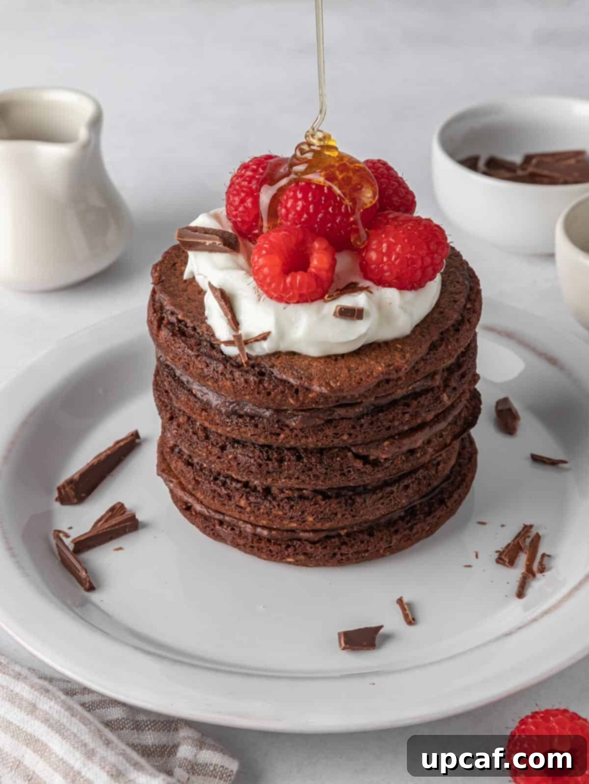 Ultimate Chocolate Protein Stacks 8 Chocolate protein pancakes topped with wipped cream and raspberries.
