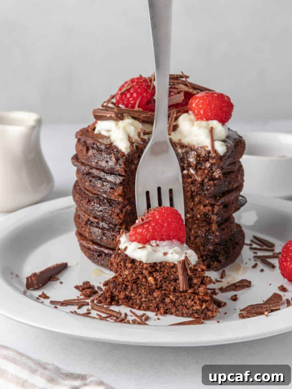 Ultimate Chocolate Protein Stacks 9 A fork picks up a bite of pancakes topped with raspberries.