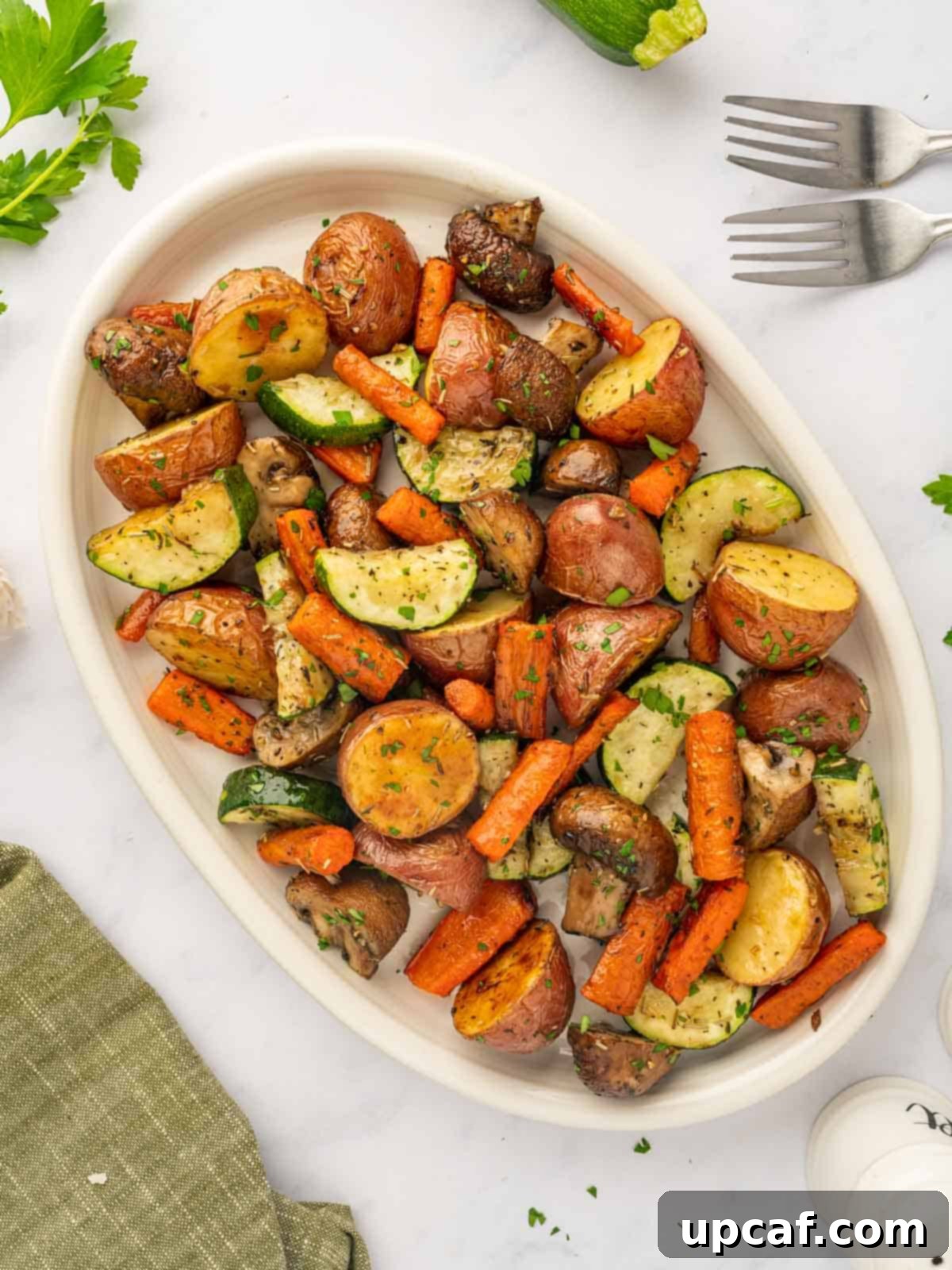 A large platter is filled with oven roasted vegetables, garnished with fresh herbs.