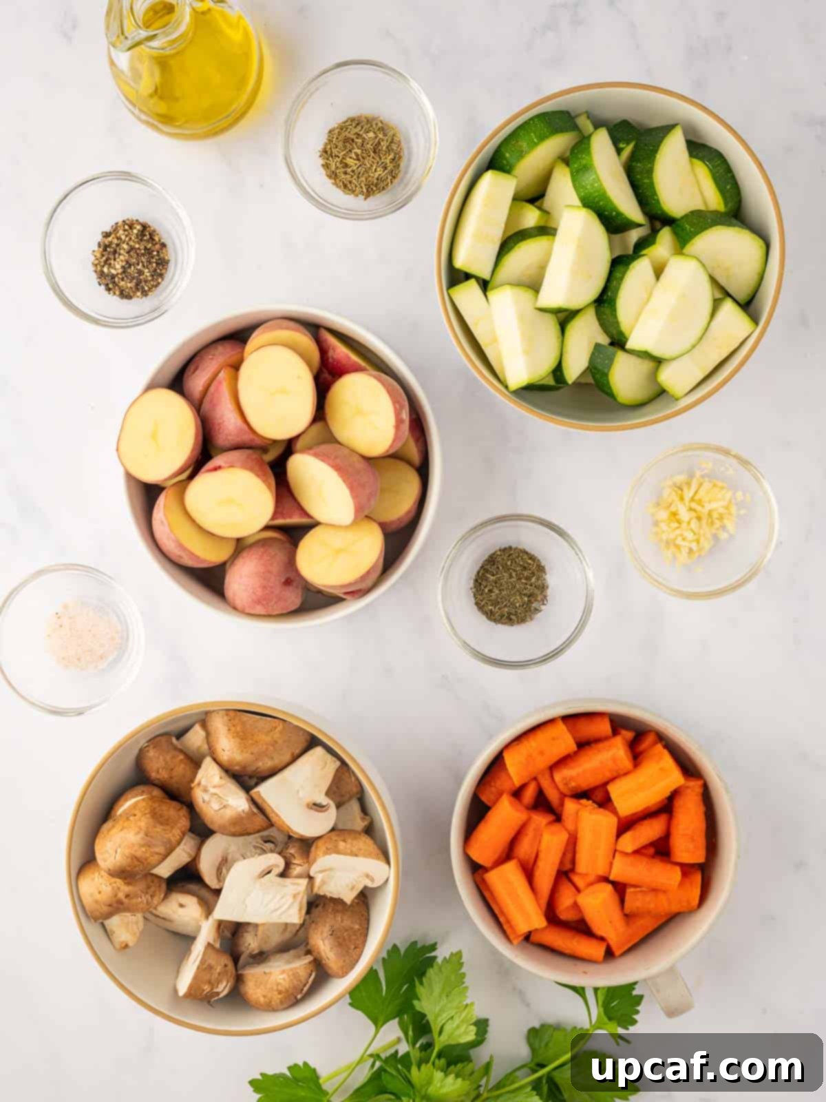 Ingredients needed for roasted veggies, including potatoes, carrots, zucchini, mushrooms, herbs, and olive oil.