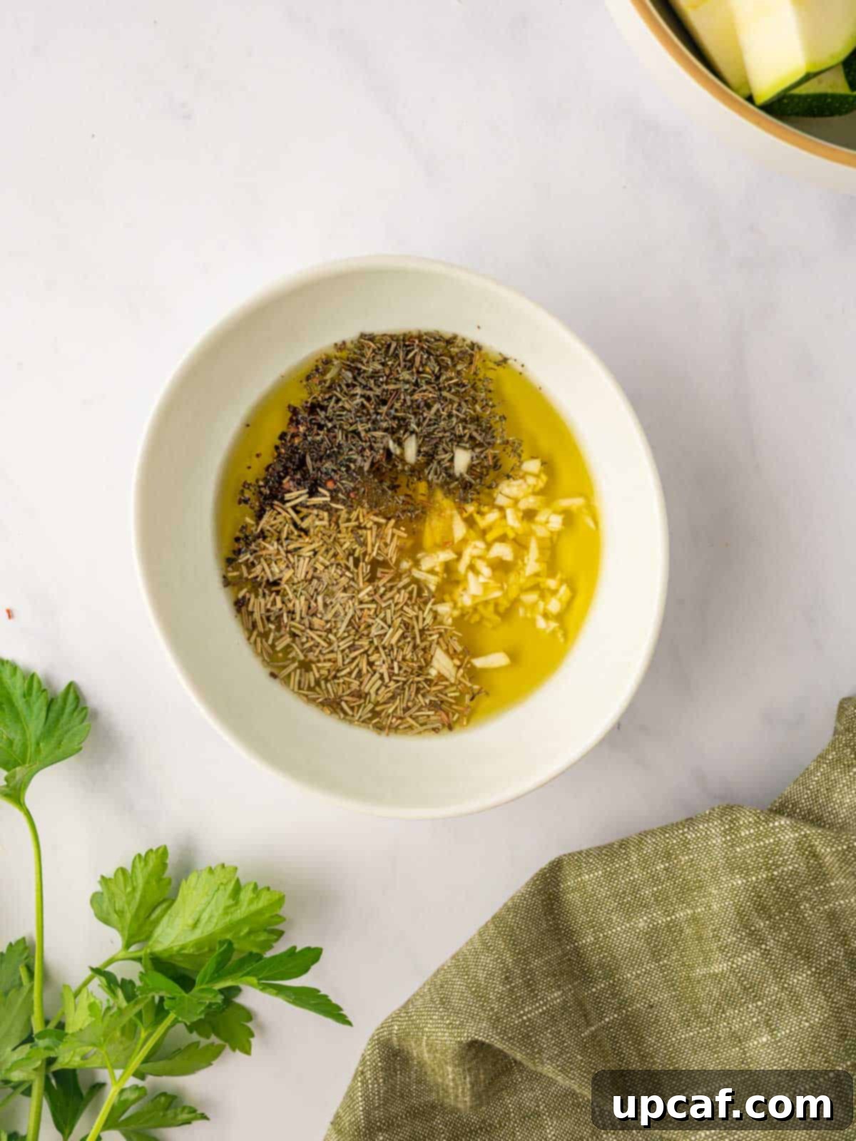 Garlic and herbs are mixed with olive oil in a small bowl.