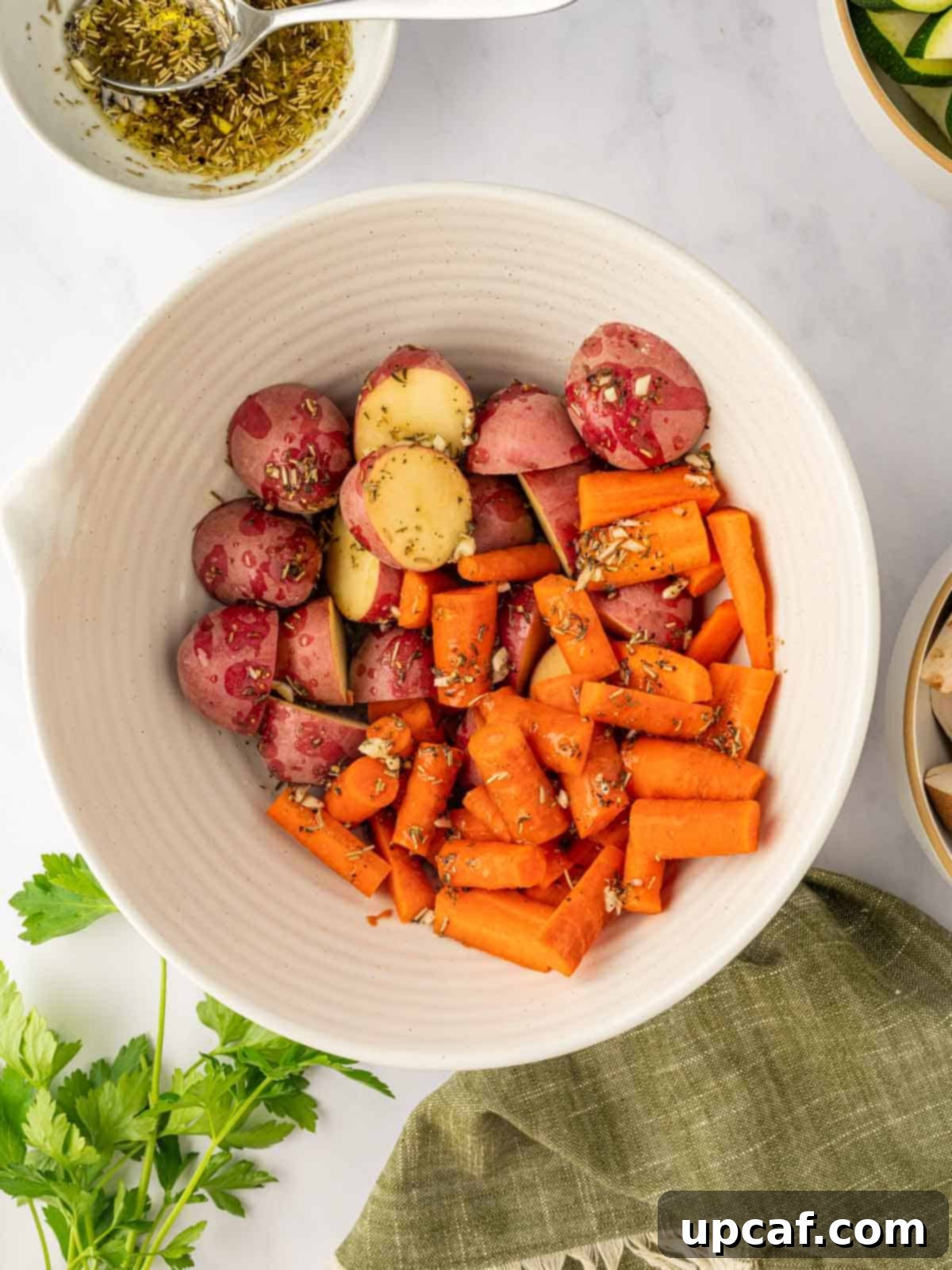 Marinated carrots and potatoes in a bowl, coated in seasoning.