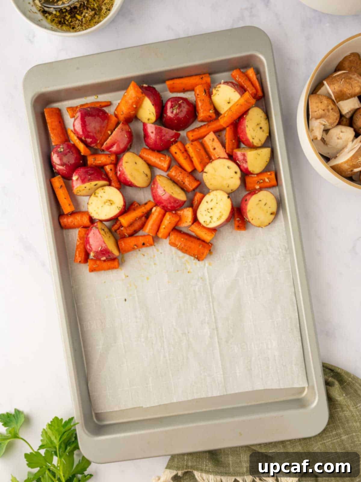 Root vegetables, carrots and potatoes, added to a baking sheet in a single layer.