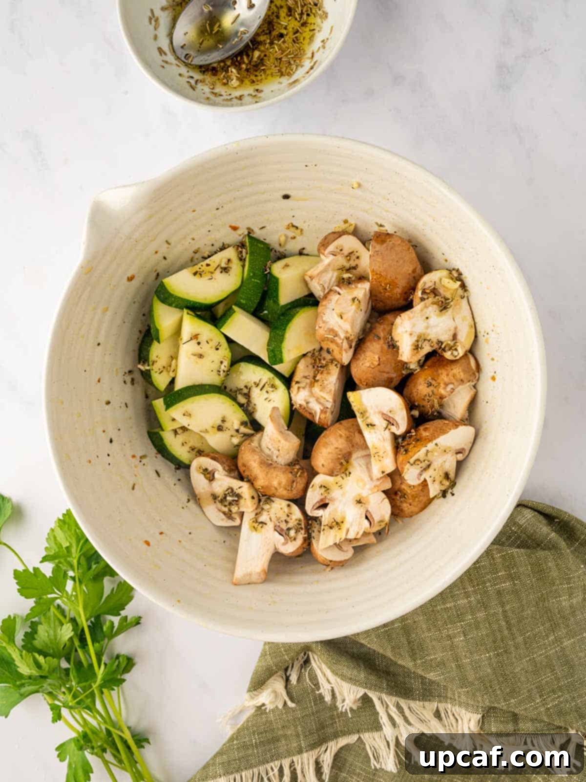 Seasoned zucchini and mushrooms in a bowl, ready to be added to the oven.