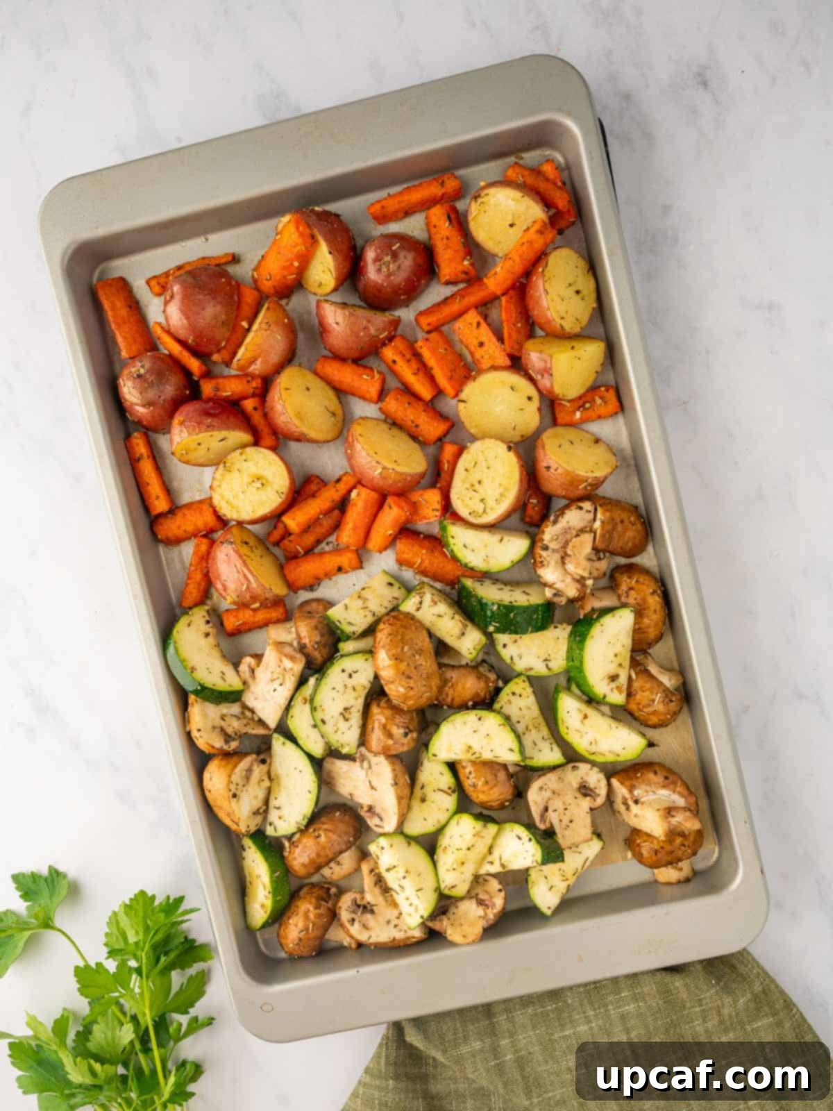All seasoned vegetables on a baking sheet, ready for the final roasting stage.