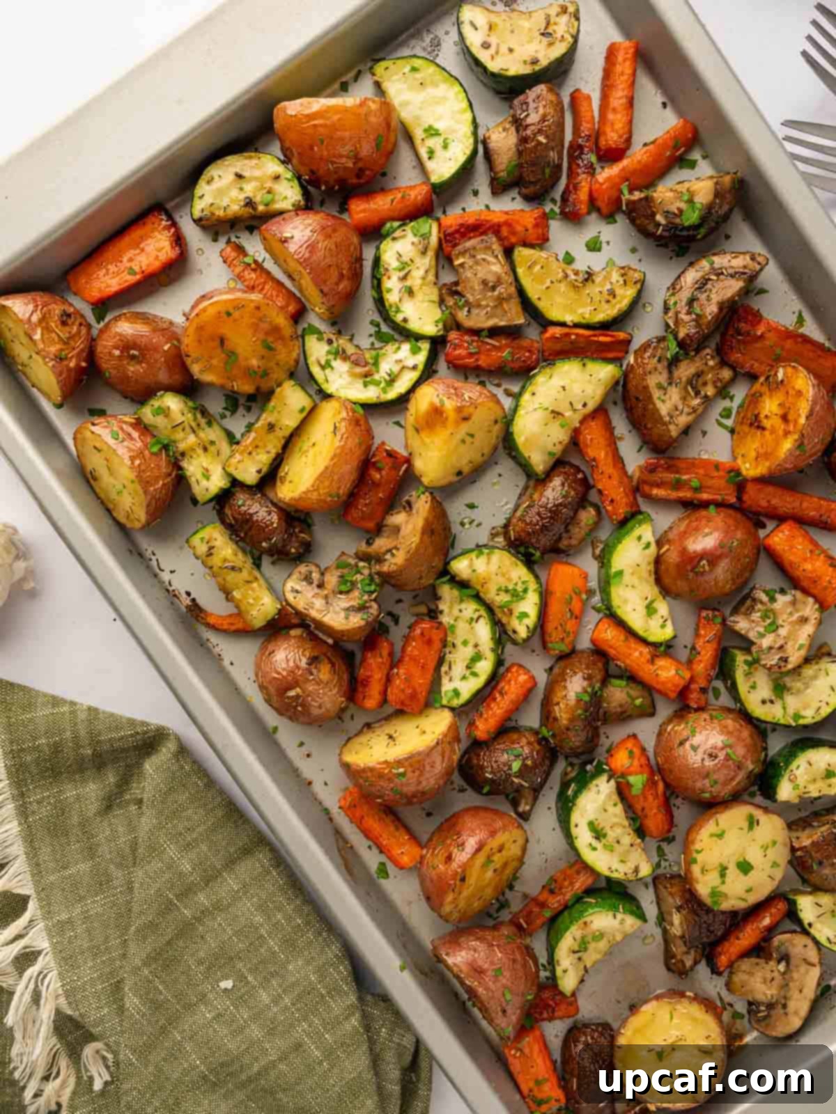 Roasted vegetables are on a baking tray, golden brown and tender.