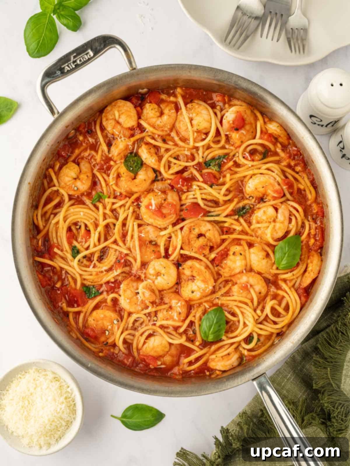 A skillet with spaghetti and shrimp in red sauce.