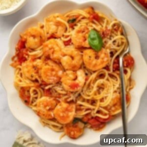 A bowl of pasta topped with sauteed shrimp.
