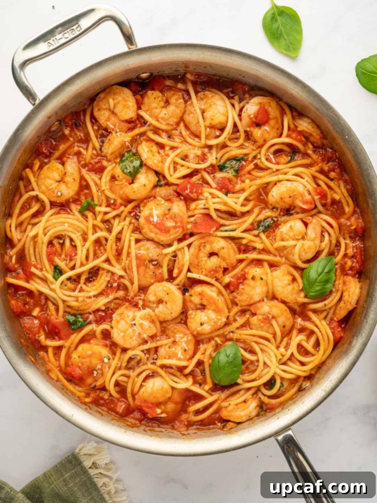 Shrimp spaghetti garnished with basil in a skillet.