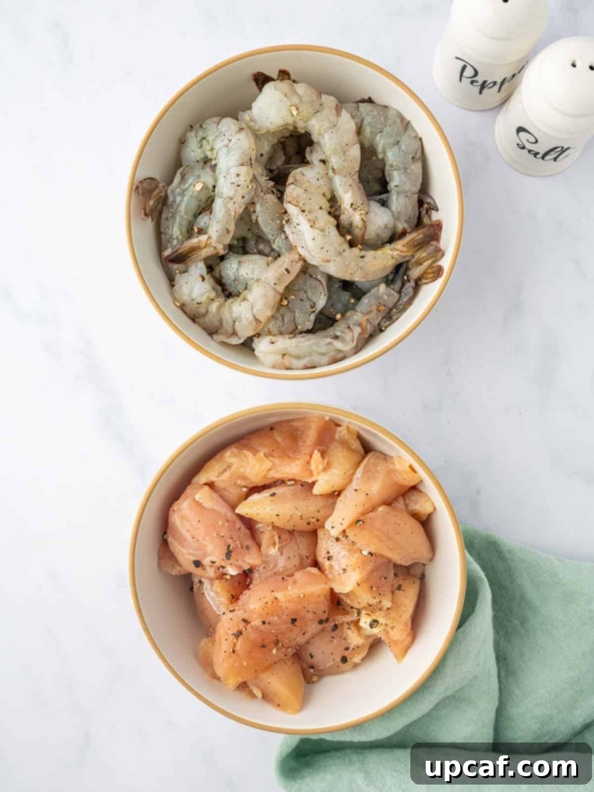 Surf and Turf Stir Fry 4 Raw chicken breast pieces and peeled, deveined shrimp seasoned with salt and pepper on a plate.