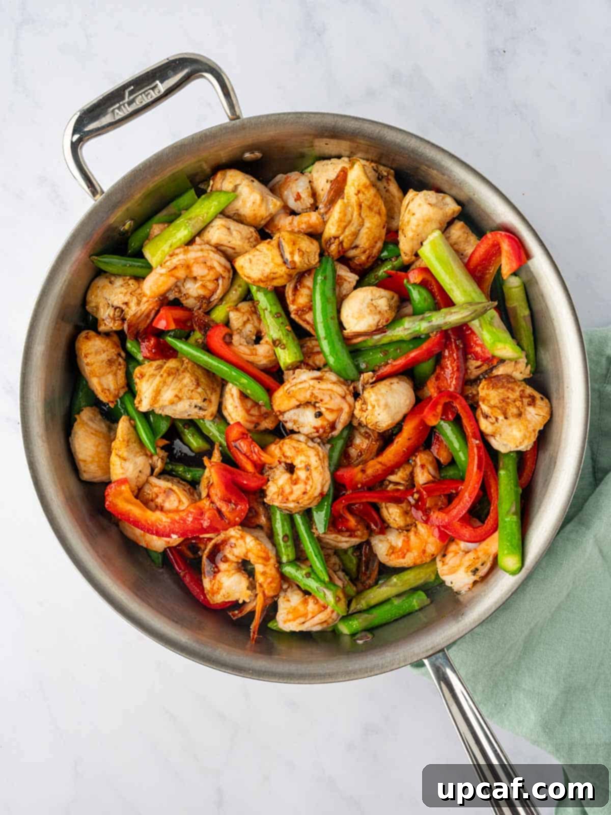 Surf and Turf Stir Fry 8 Cooked chicken, shrimp, and stir-fried vegetables combined in a large skillet, ready for sauce.
