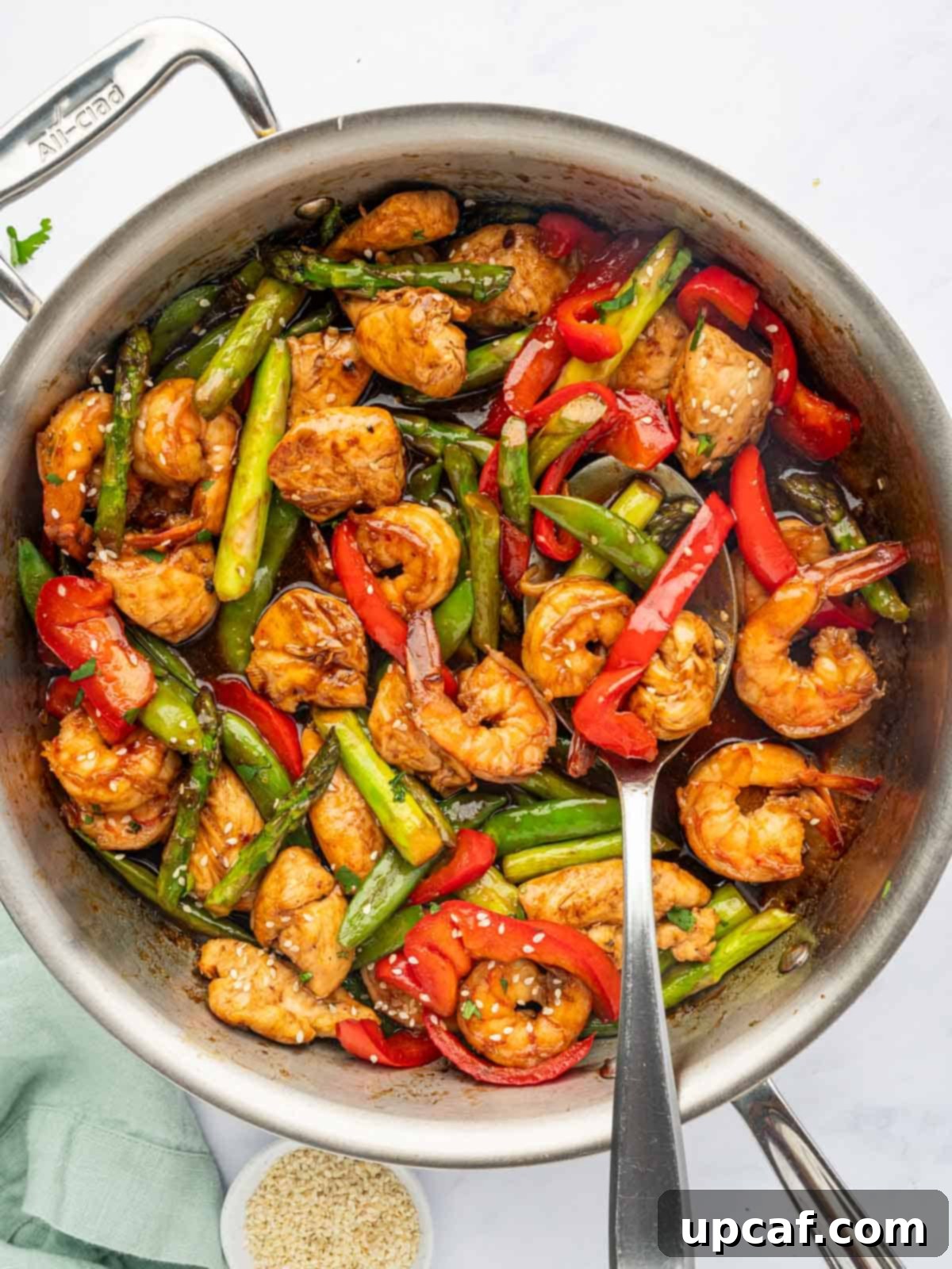 Surf and Turf Stir Fry 9 A serving spoon lifting a portion of chicken and shrimp stir fry from a pan, showing off the vibrant ingredients.