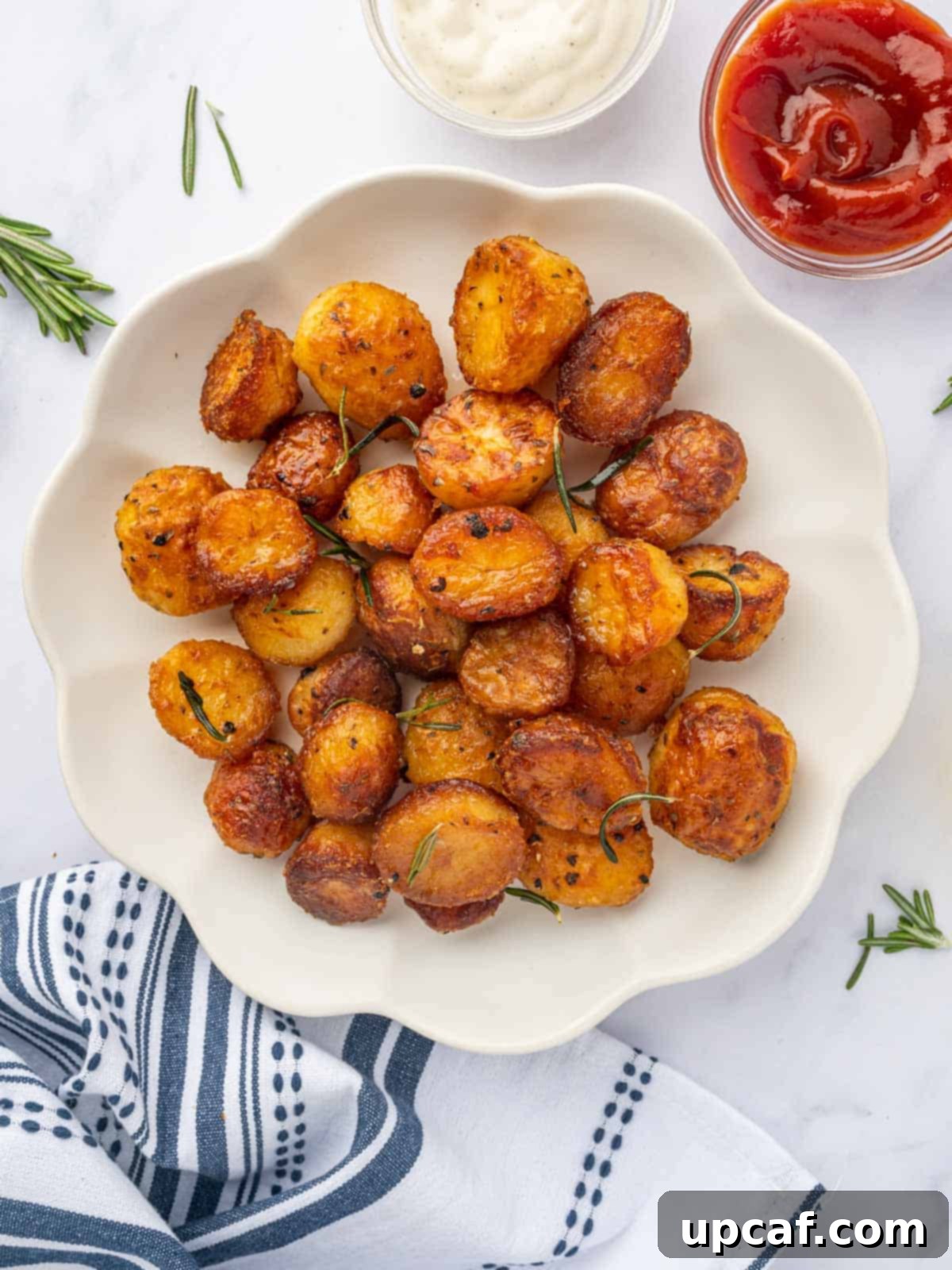 A plate of baked baby roasted potatoes with dipping sauces, showcasing their golden-brown crispness.