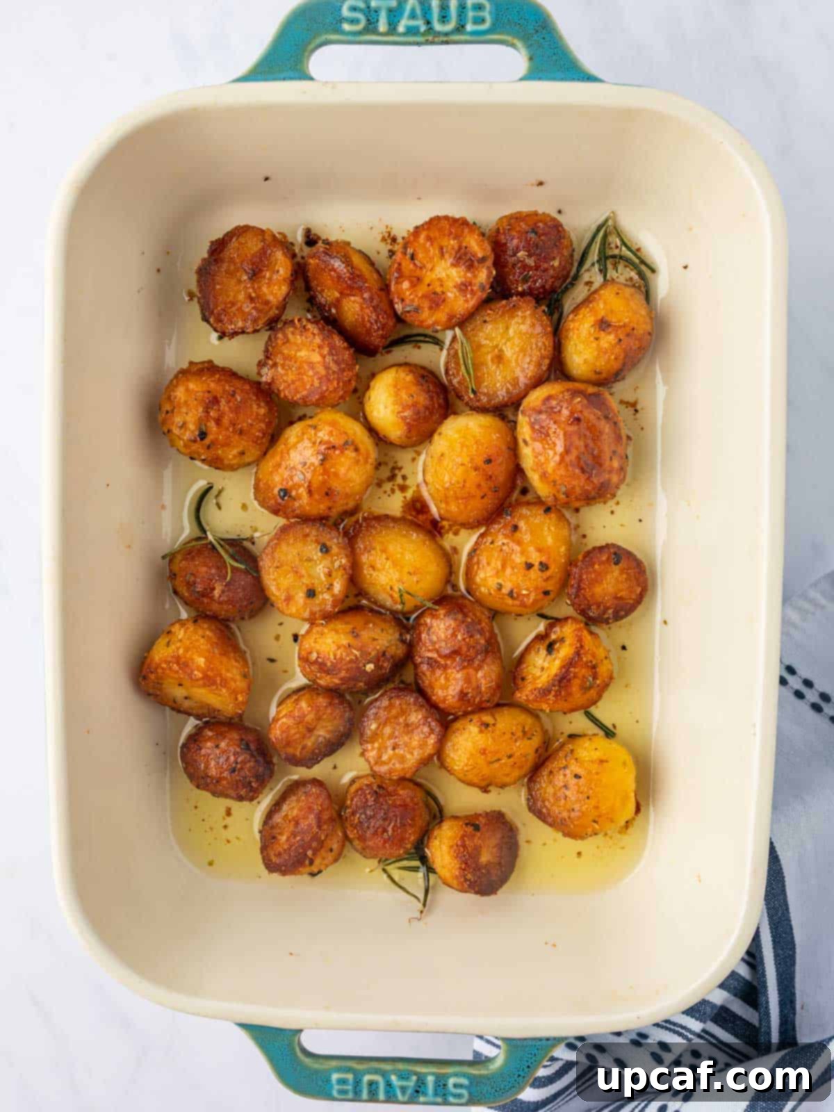 A casserole dish filled with crispy, golden-brown roasted baby potatoes, fresh out of the oven.