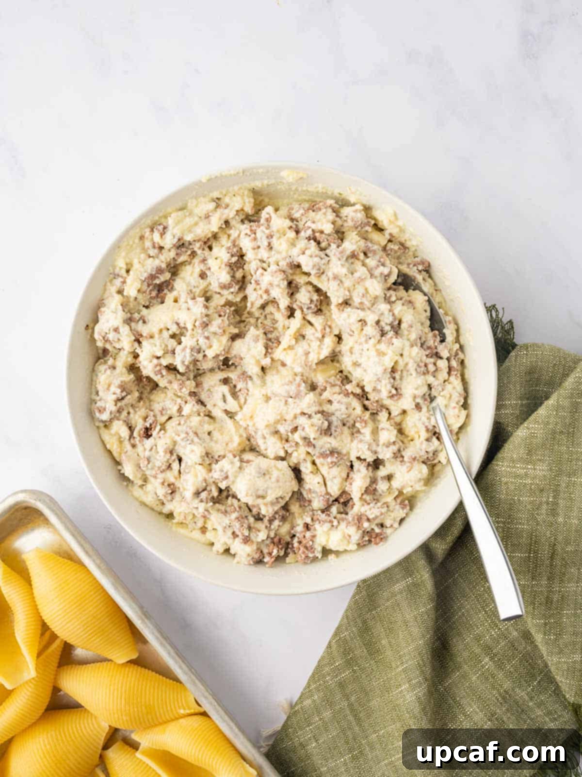 Hearty Beef and Ricotta Stuffed Shells 8 The savory ground beef portion added to the creamy ricotta cheese mixture in a bowl, being mixed for the ultimate shell filling.