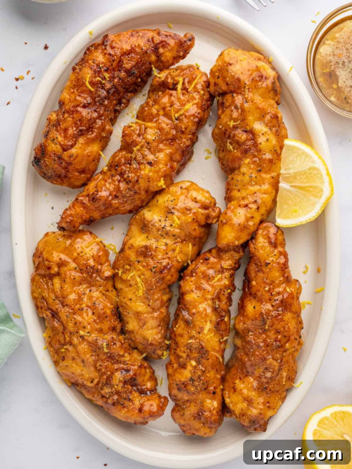 Crispy baked lemon pepper chicken strips with honey glaze.