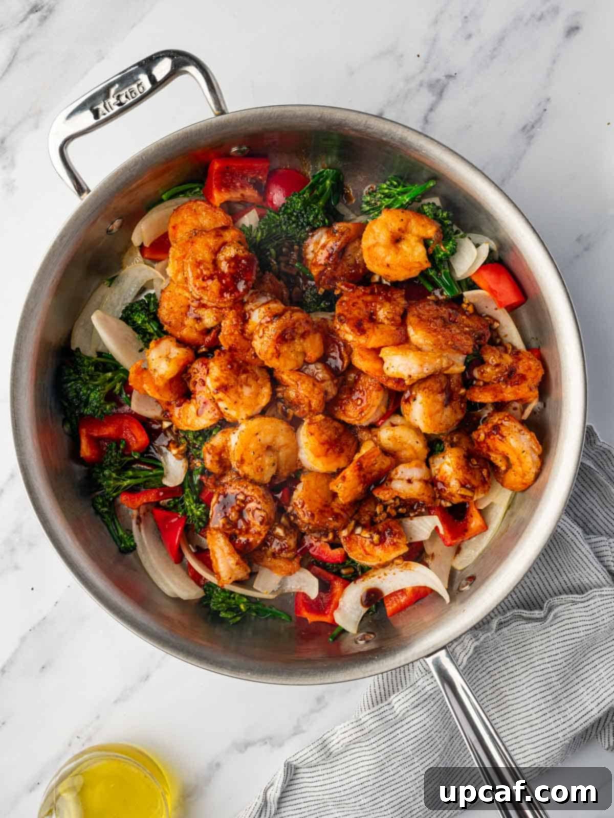 Panda Express copycat shrimp and vegetables coated in sauce in a skillet.