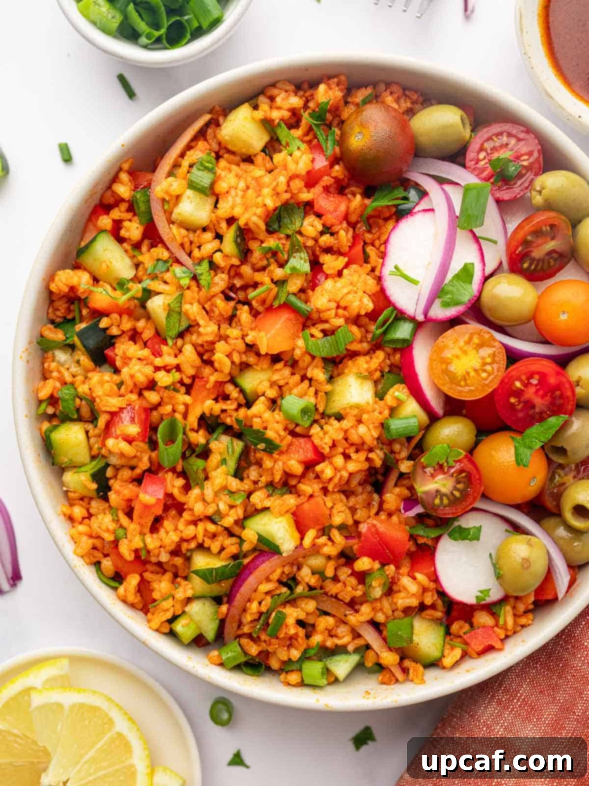 Bowl of Turkish Kisir Salad garnished with fresh tomatoes, black olives, and thinly sliced radish, ready to be served.