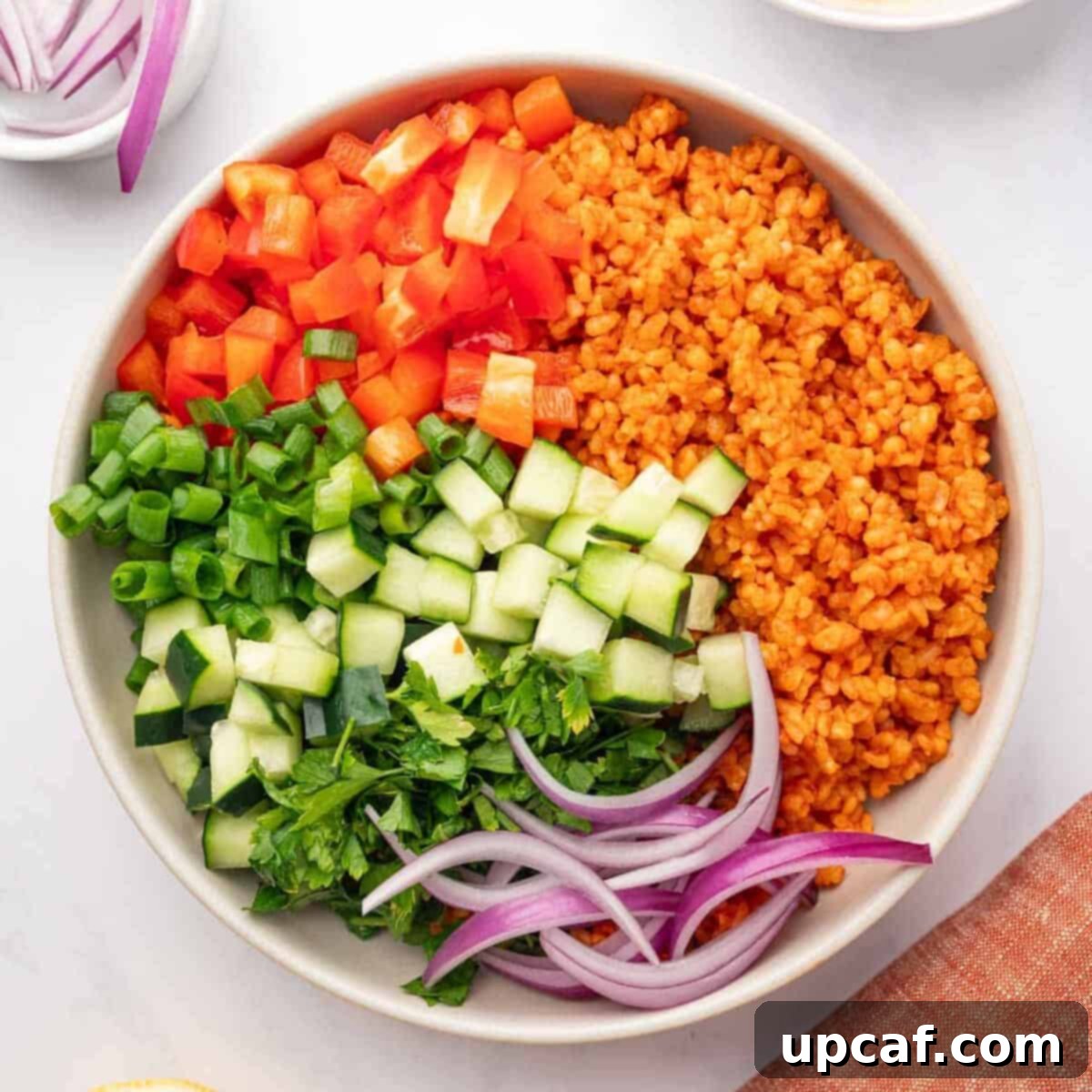 Ingredients of kisir salad, including bulgur, mixed vegetables, and a bowl of dressing, arranged before final combination.