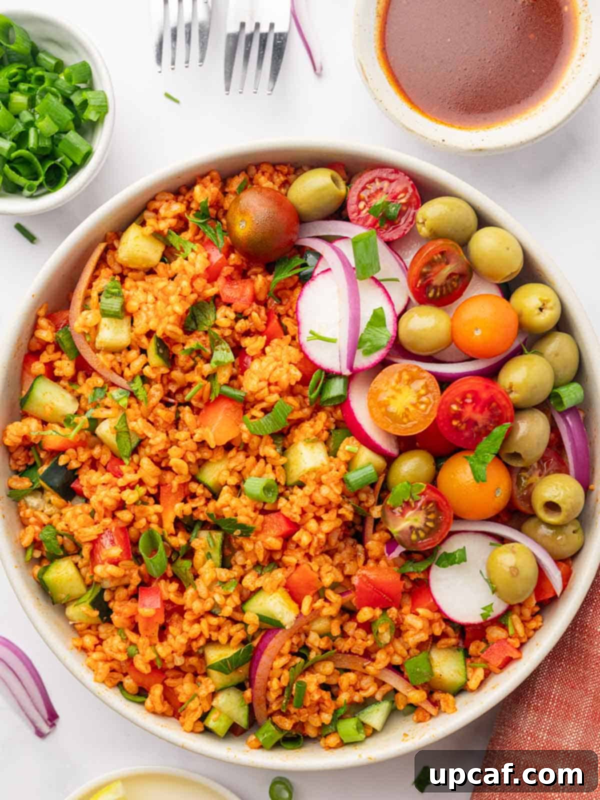 Bowl of Turkish Kisir Salad garnished with tomatoes, olives, and radish, beautifully presented for serving.