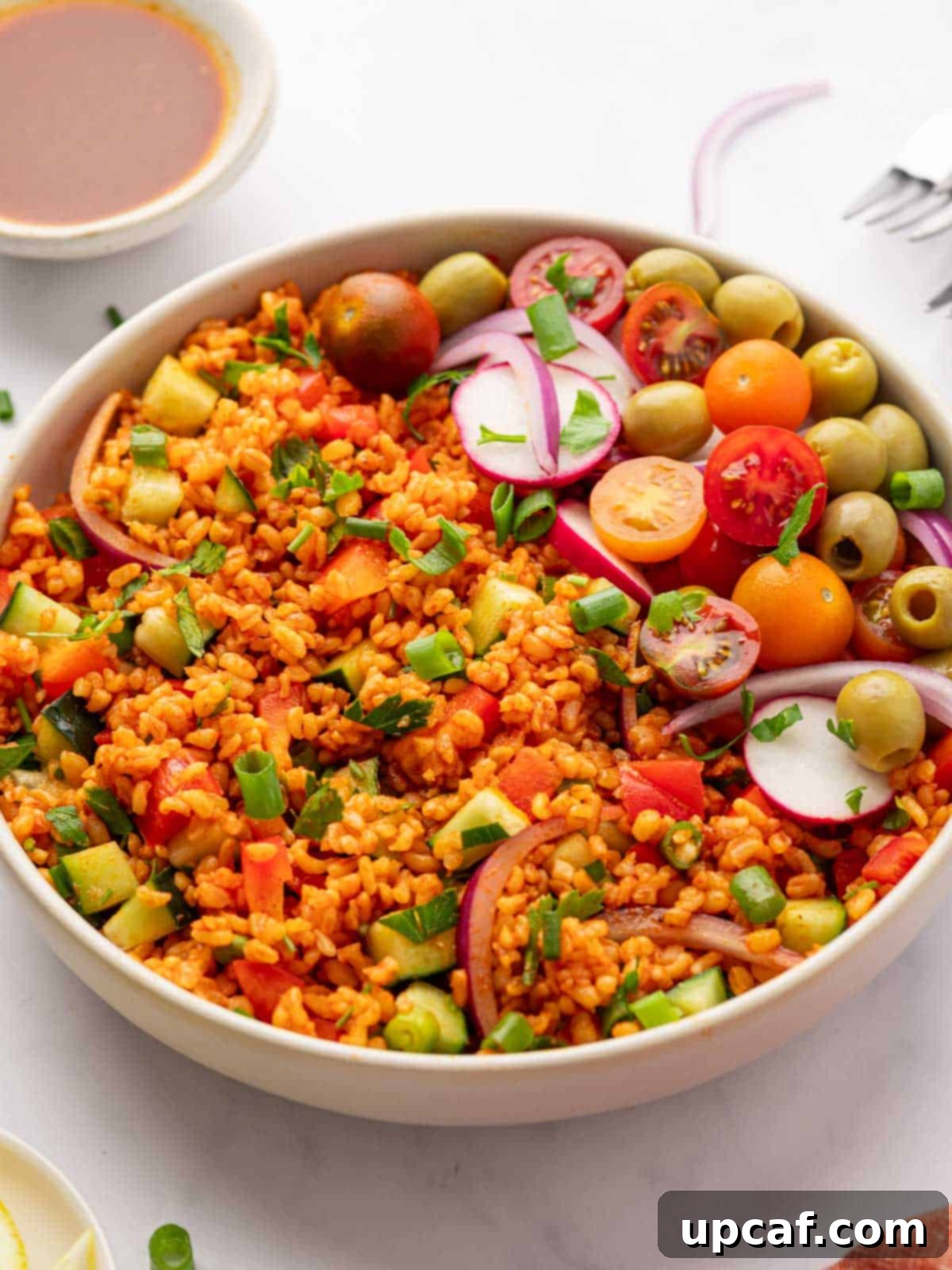 Bowl of vibrant Turkish Kisir Salad, garnished with tomatoes, olives, and radish, beautifully lit and ready to be enjoyed.