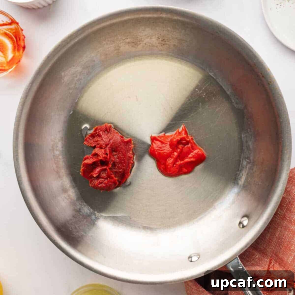 Tomato paste and red pepper paste mixture in a shallow pan before cooking, with olive oil.