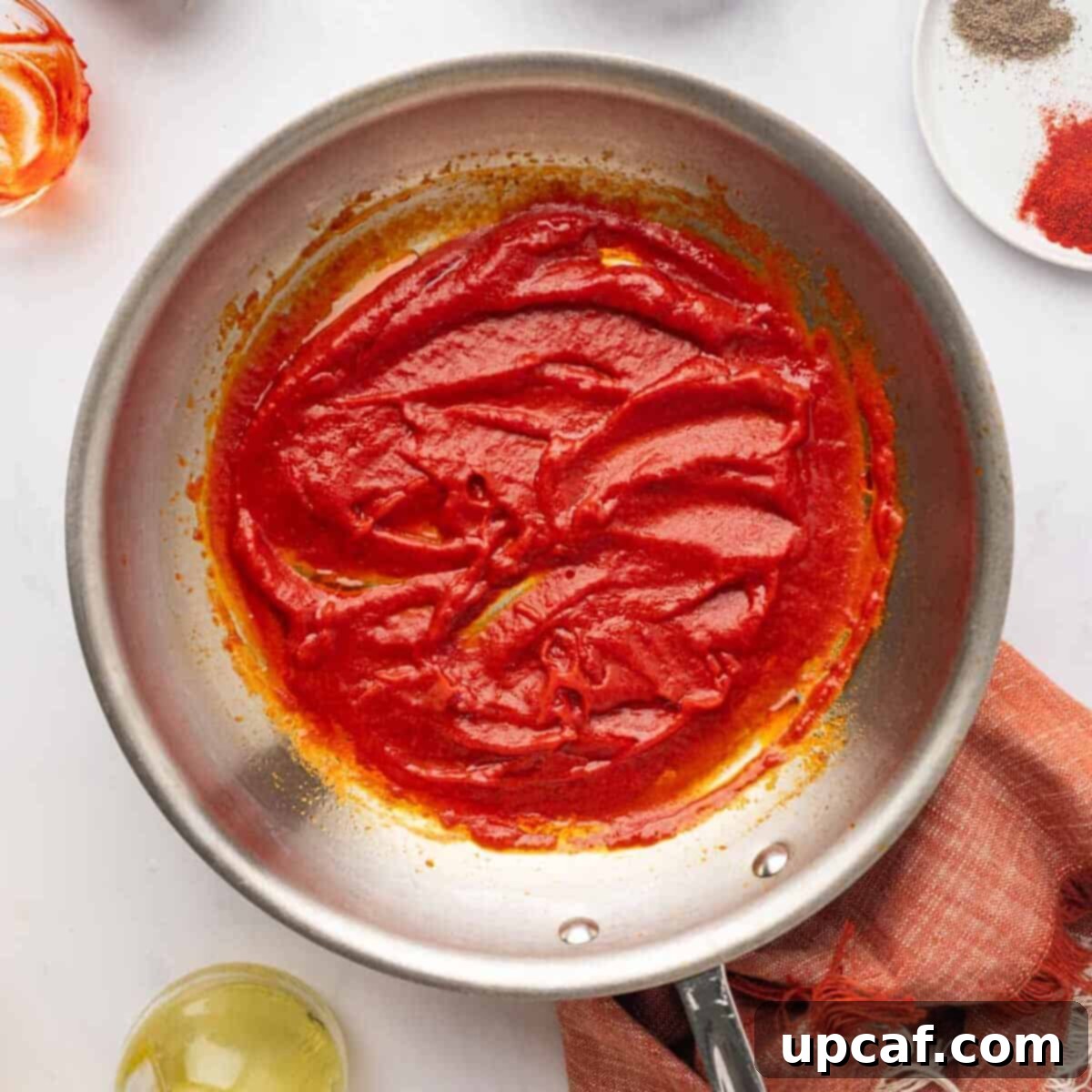 Cooked tomato and red pepper paste mixture in a pan, glossy and rich in color.