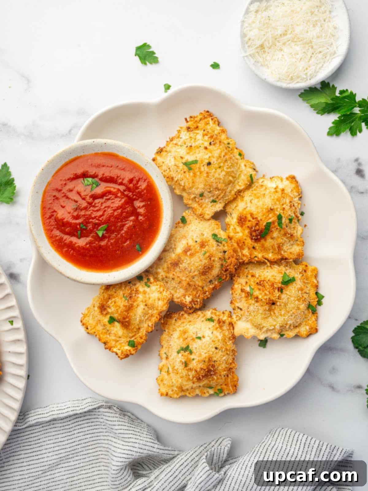 A platter of air fryer ravioli with marinara sauce for dipping.