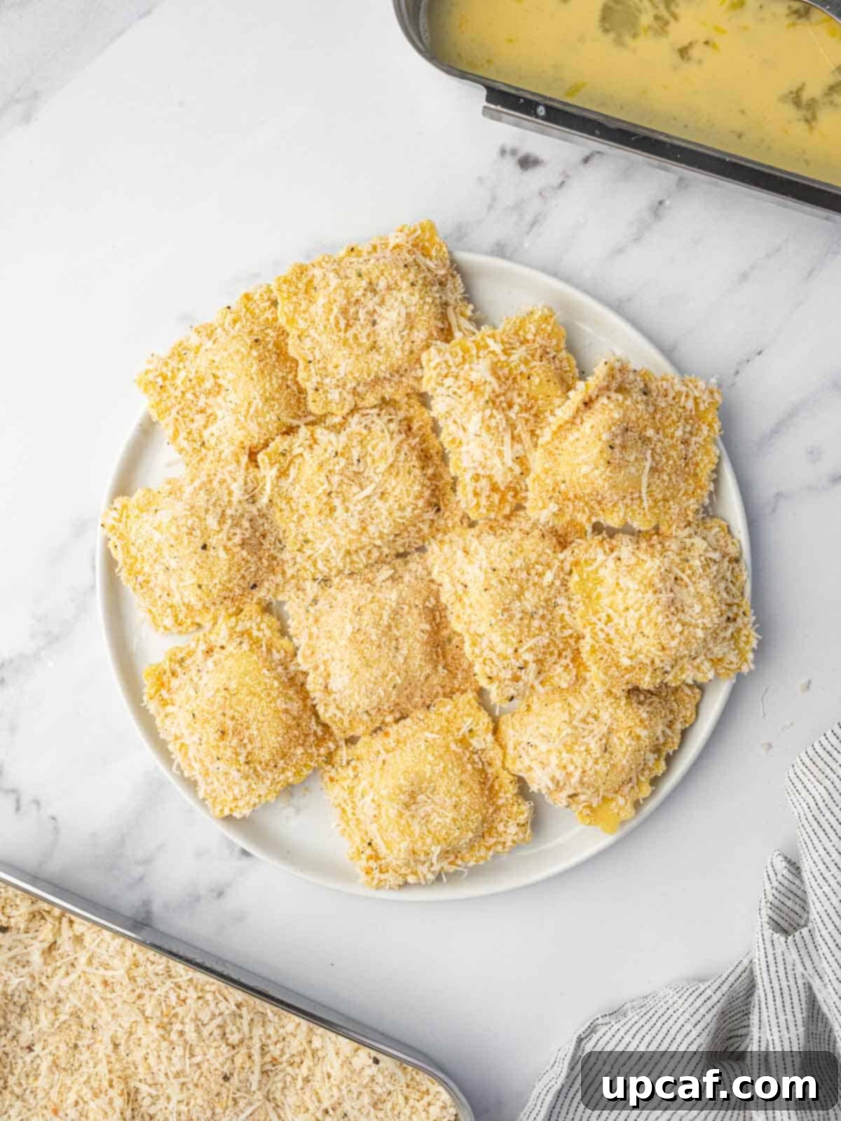 A platter of breaded ravioli prepared for air frying.