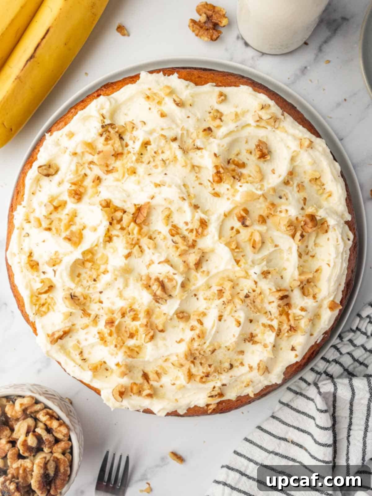 Top view of banana walnut cake on a platter, showcasing its rich texture and generous walnuts.