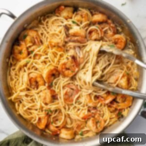 Tongs scoop up a serving of cajun shrimp pasta.