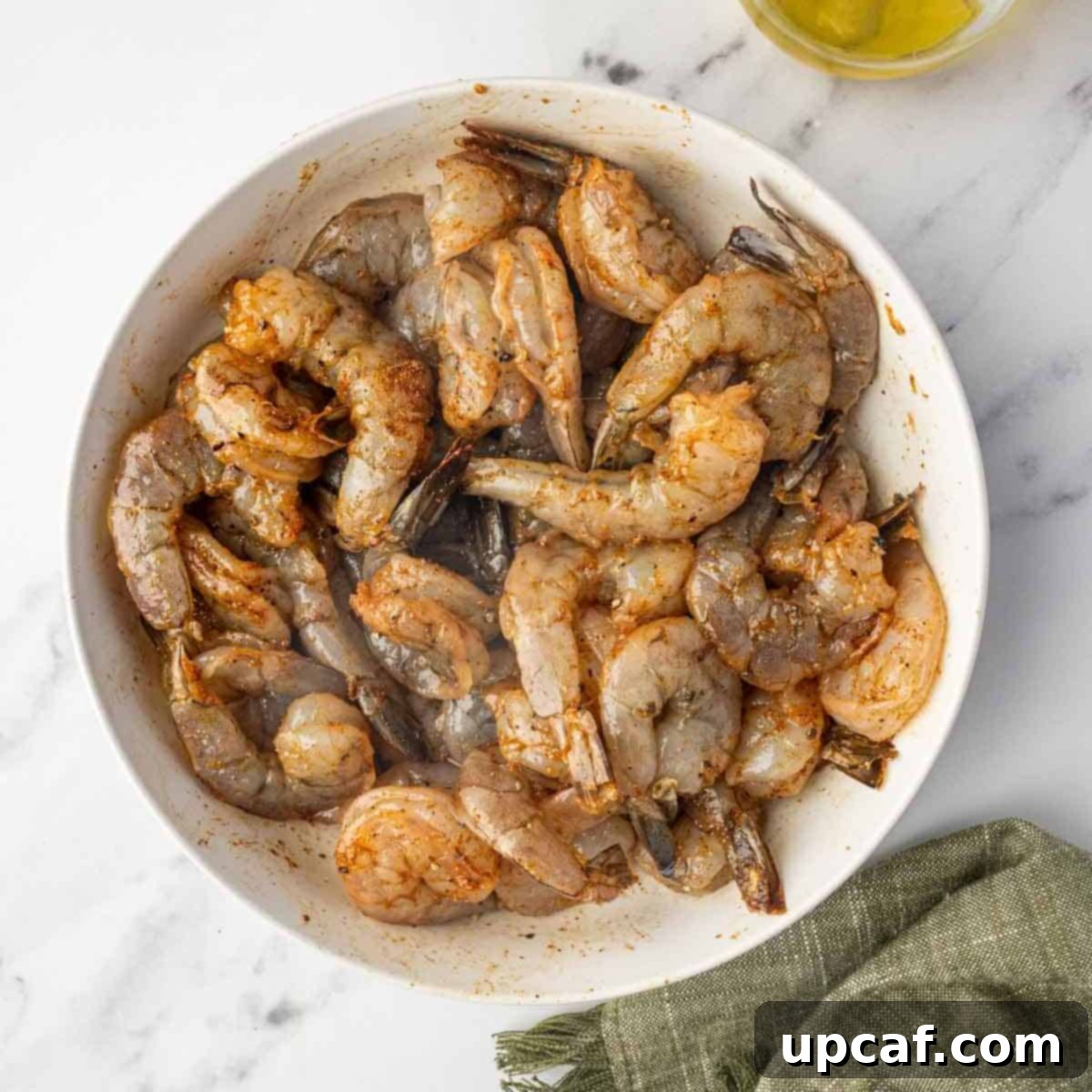 Marinated cajun shrimp in a bowl, ready for cooking.