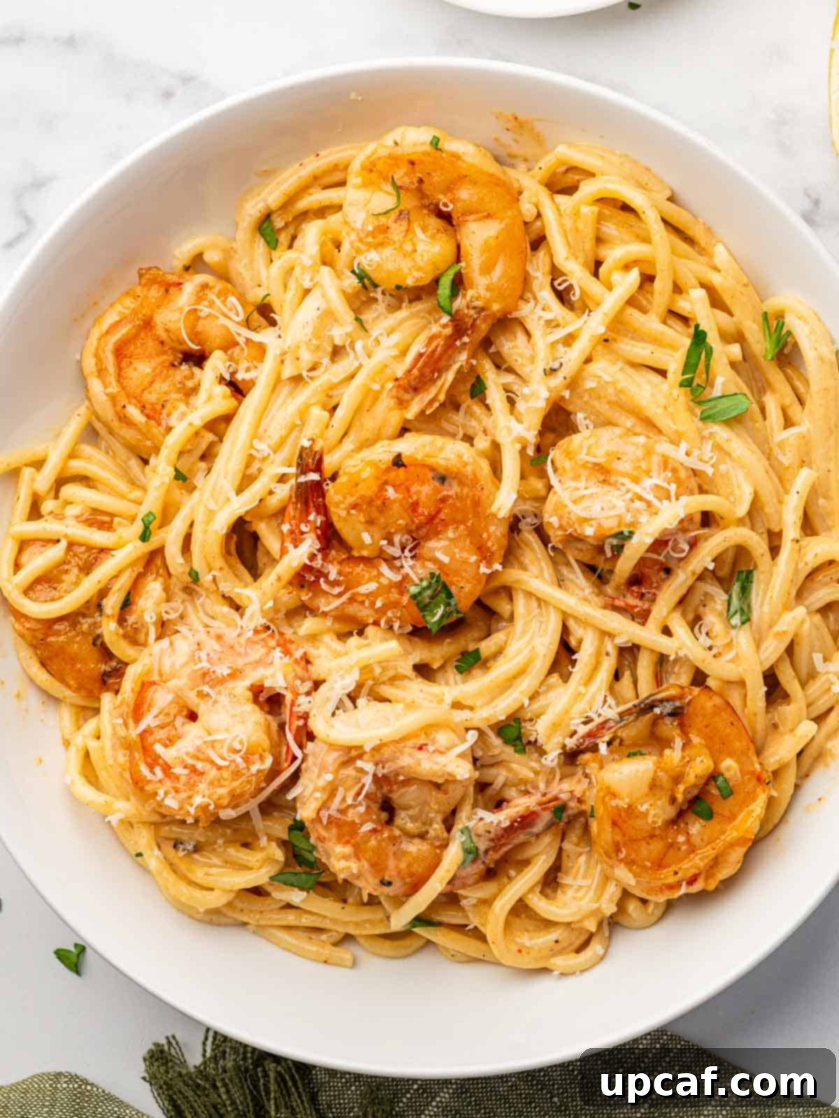 A perfectly portioned serving of Cajun Shrimp Scampi with pasta on a white plate, ready to be enjoyed.